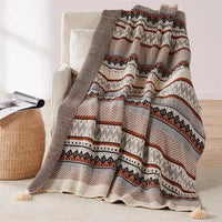 Bohemian striped knit throw with geometric pattern and pompom trim