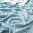 Nordic-style knitted throw with pom-poms and check pattern