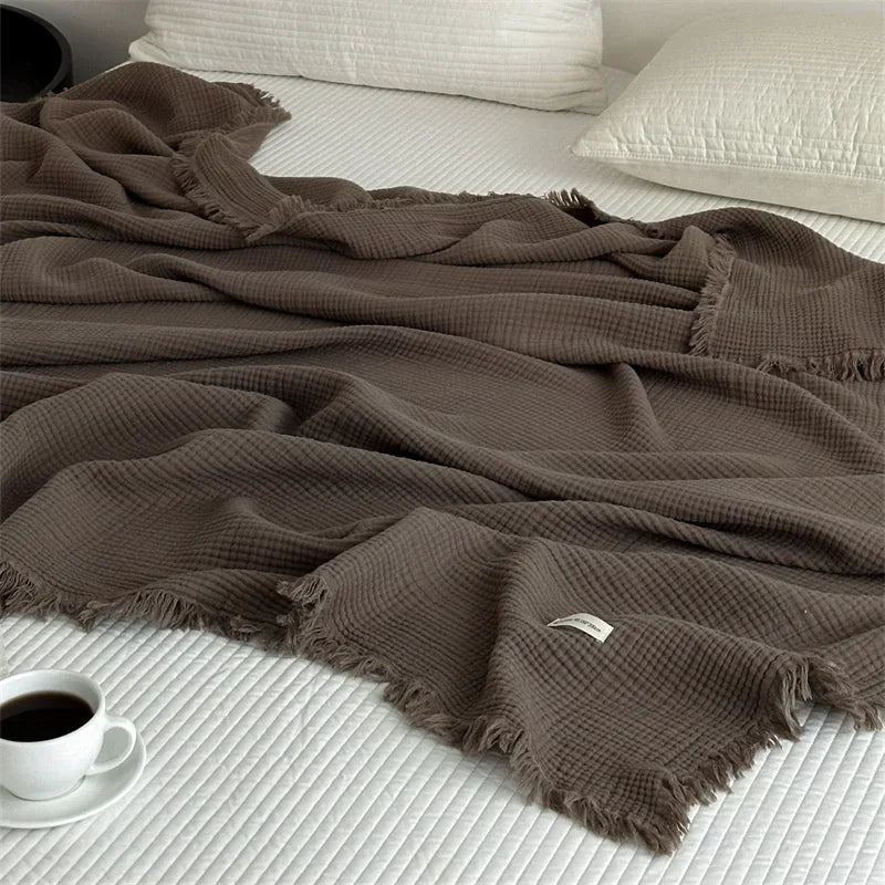 Soft plain cotton throw with pompoms for living room