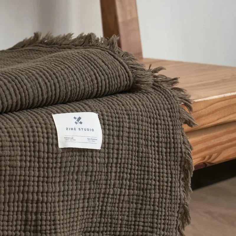 Lightweight cotton muslin throw with bohemian pompons for living room