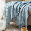 Nordic-style knitted throw with pom-poms and check pattern