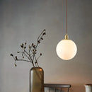 Minimalist brass pendant light with milky glass orb