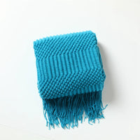 Soft knitted throw with decorative pom poms and check pattern