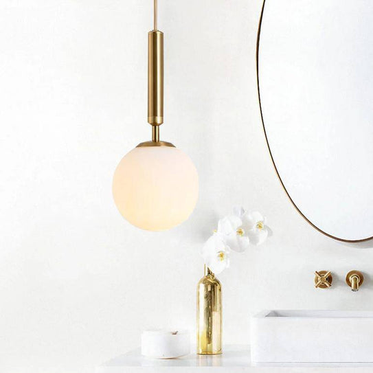 Gold tube pendant light with glass globe for bar