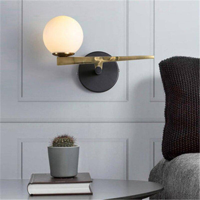 Gold wall light with glass globe