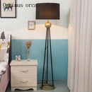 Design LED floor lamp with three connected legs, golden sphere and fabric shade